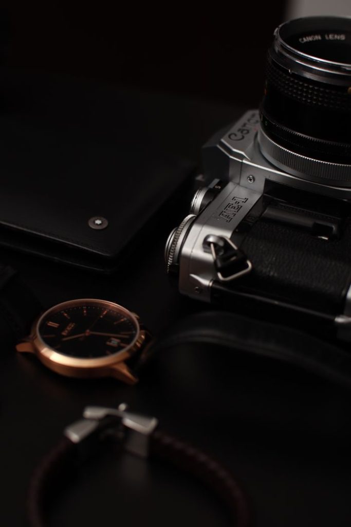 A stylish flat lay of a vintage camera, elegant wristwatch, and accessories.