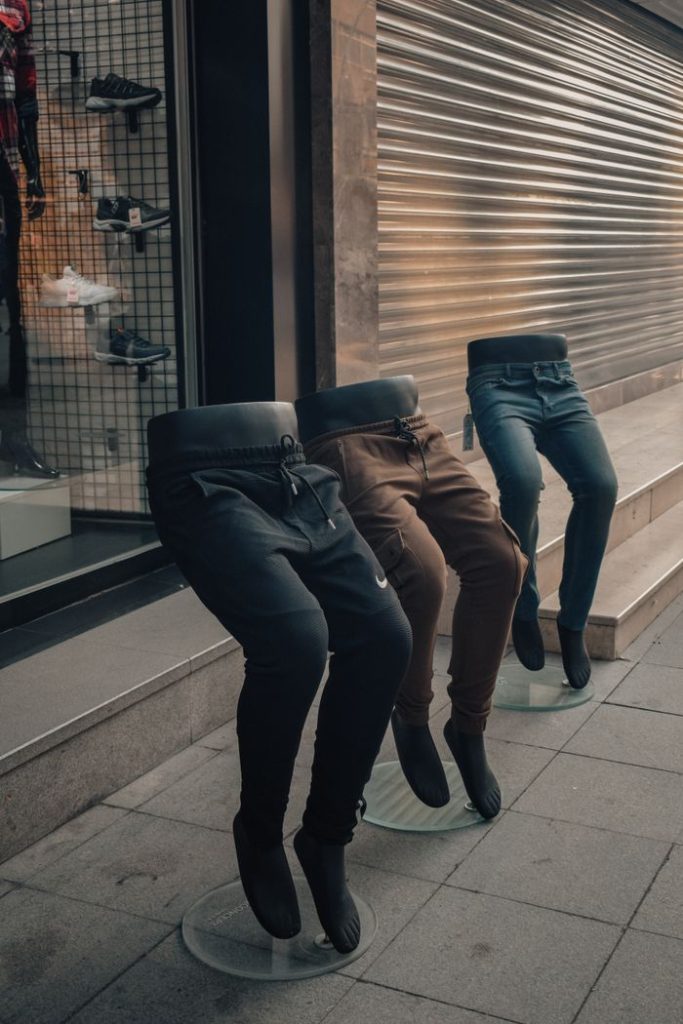 Mannequins showcasing trendy joggers outside a store on a sidewalk.
